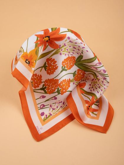 An orange floral pocket square folded to highlight its vibrant colors and pattern.