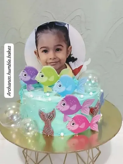 A personalized cake for a little girl who loves fish, featuring her photo as the centerpiece.