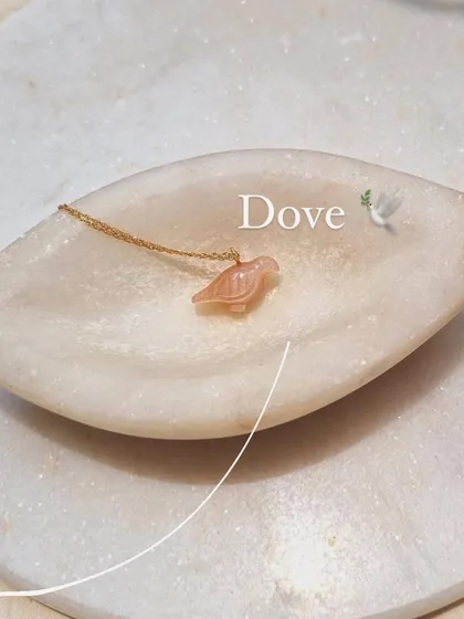 The 'dóve' pendant in peach moonstone, a beautiful symbol of peace and good fortune.