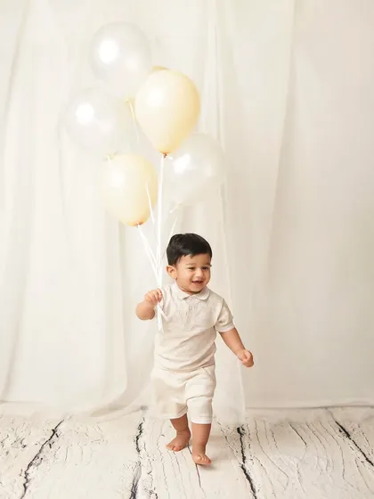 A little boy takes his first steps, holding a bouquet of balloons. This is a huge milestone, and a photoshoot is a wonderful way to celebrate it.