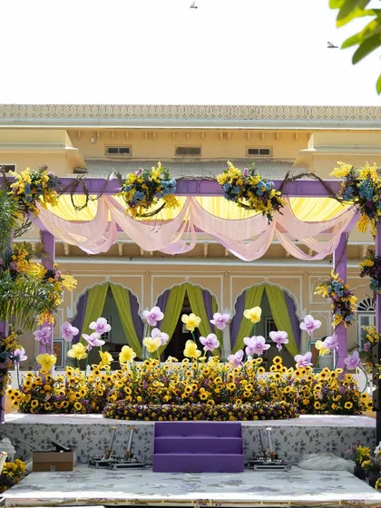 The main stage for the pastel Haldi, featuring a backdrop of sunflowers and a canopy of pink and yellow drapes.