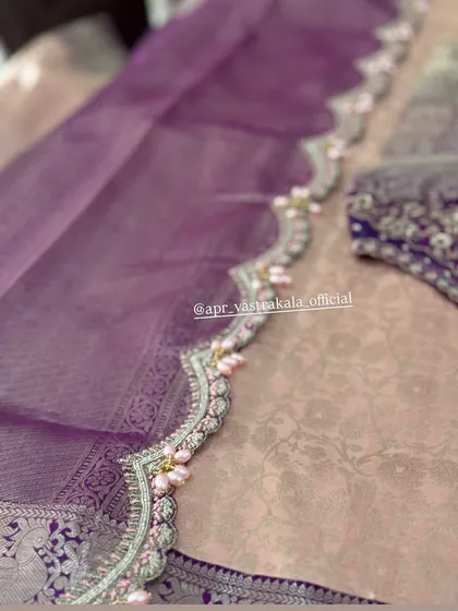 A scalloped border in lavender, detailed with silver zardosi and delicate pink pearl clusters, adding a soft, romantic touch.