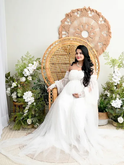 A regal pose in the peacock chair. Surrounded by white florals, the mom-to-be looks like a queen on her throne in this elegant boho-style portrait.