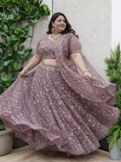 The beautiful flare of this dusty-mauve plus-size lehenga is captured perfectly in this twirling shot. The soft color and delicate floral embroidery make it a romantic and elegant choice for any special event.