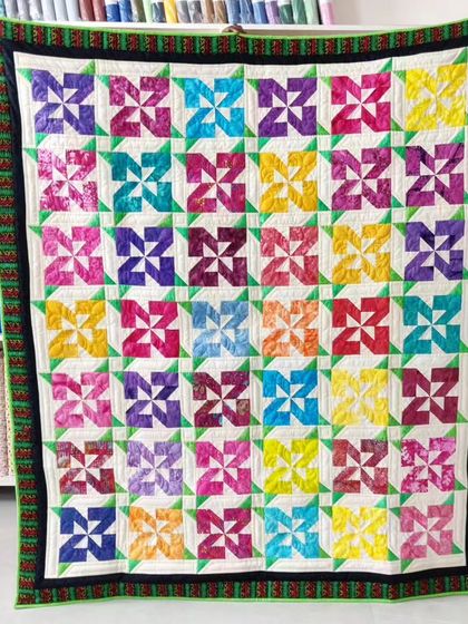 A vibrant quilt made of colorful pinwheel blocks.
