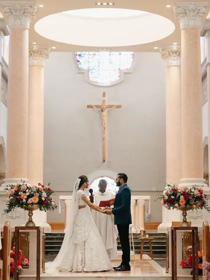 A sacred union sealed at the altar. The bride's custom white lehenga and the groom's unconventional teal tuxedo create a striking contrast that is both modern and deeply personal.