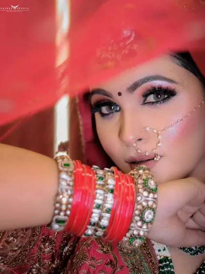 A close-up shot through the red veil, focusing on the bride's eyes and bangles.