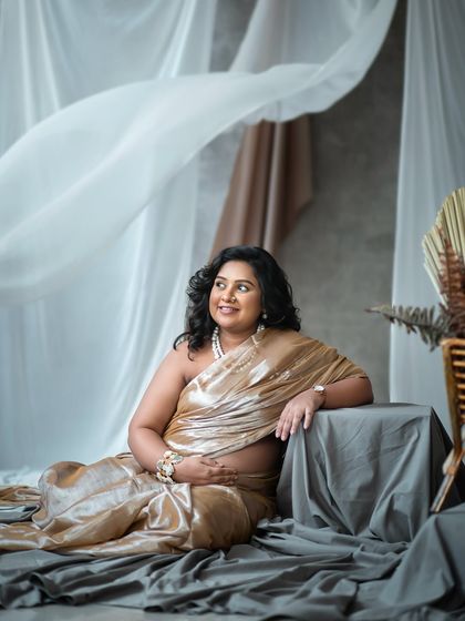 A serene and graceful pose, showcasing the beauty of the expecting mother in a shimmering golden saree.