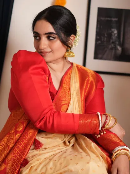 A close-up of the Bengali drape, showing the beautiful red and cream color combination and traditional accessories.