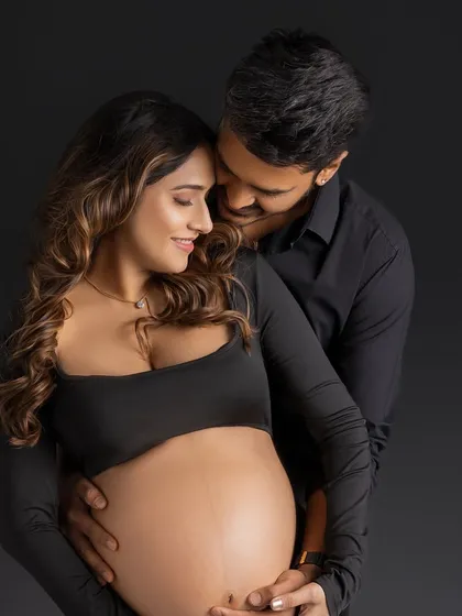 A beautiful embrace from behind, filled with smiles and the shared joy of pregnancy.