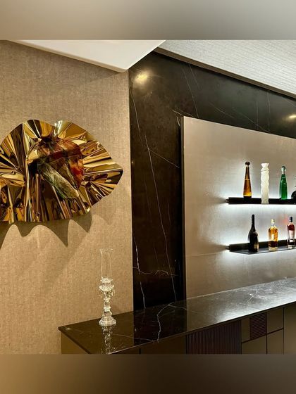 The play of light and shadow on the golden sculpture makes it a dynamic addition to the sophisticated bar design.