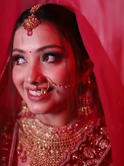 A candid, smiling portrait of the bride looking away. The soft red lighting creates a warm and romantic atmosphere.
