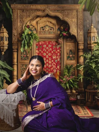 We specialize in creating stunning traditional maternity portraits. This image showcases a beautiful mom-to-be in a classic saree, set against a richly detailed, ethnic-themed backdrop in our Bangalore studio.