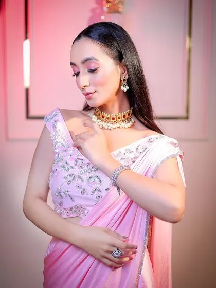 A soft and elegant portrait in a pink saree, using gentle pink-toned lighting to complement the outfit.