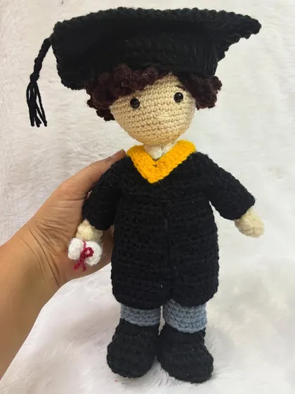 Holding the graduation doll to show its size. It's a thoughtful and unique gift that commemorates a major milestone.