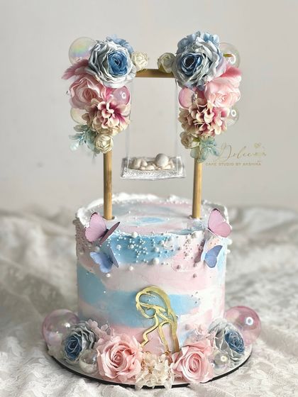 A beautiful gender reveal swing cake with a mix of pink and blue flowers. The swing structure is versatile and can be customized for any theme.