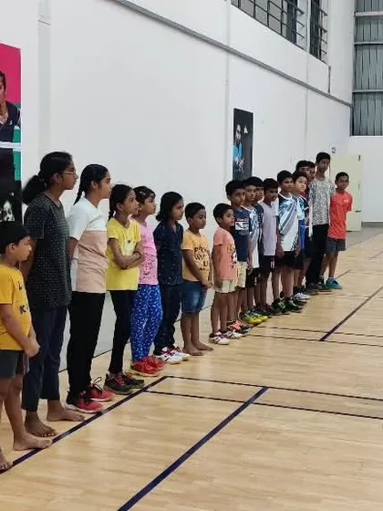 A coach lining up young students to explain a footwork drill, demonstrating our organized approach to beginner classes.
