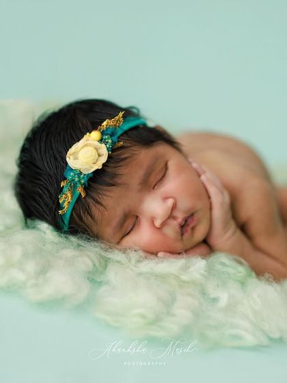A slightly different angle of this peaceful pose, highlighting the baby's profile and the delicate floral headband. The soft green wool adds a lovely texture.