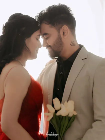An intimate close-up of a couple, their foreheads touching, in a bright and airy studio setting.