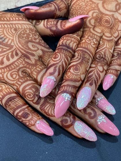 A close-up of a detailed pink bridal set against the client's mehendi. The design includes glitter, sugar effects, and delicate rhinestone clusters.