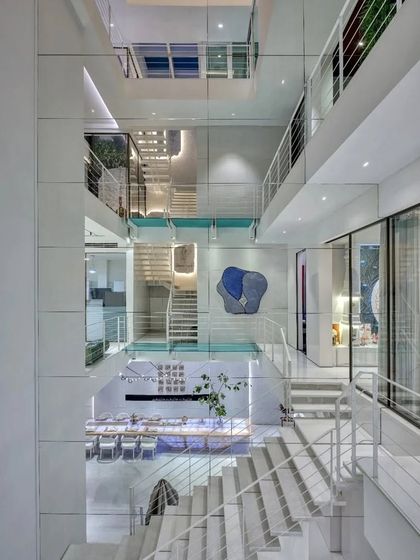 The multi-level, open-atrium design of the award-winning 'Vrinda' project. The white-on-white palette and glass bridges create a sense of infinite space and light.