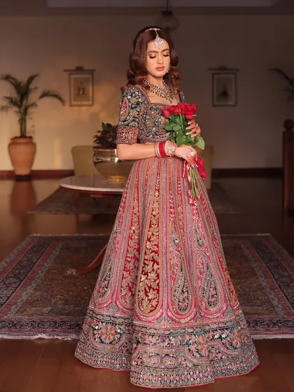 A portrait of the bride holding roses, giving a clear view of the beautiful embroidery on the blouse and the overall richness of the lehenga.