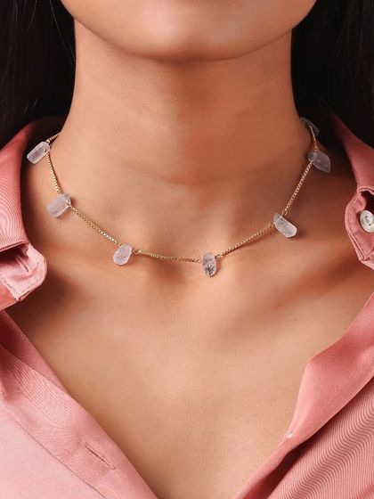 A tight close-up on a model's neck, providing a clear and detailed view of a delicate stone choker necklace.