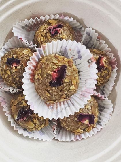 A close-up of my almond and walnut laddus. These energy balls are presented in a biodegradable bowl, garnished with delicate rose petals, showcasing their handmade quality.