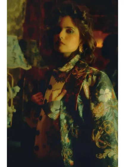 A portrait from the final chapter. The styling combines a floral jacket with a modern knit, a final synthesis of her past and future. The mood is confident and forward-looking.