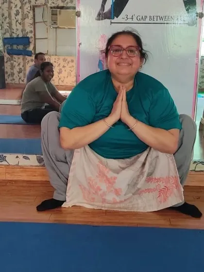 A student smiling in Malasana (Garland Pose). This deep squat is fantastic for opening the hips and strengthening the ankles and lower back.