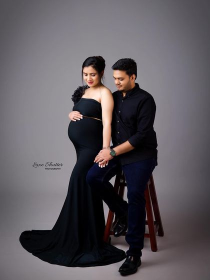 This seated pose offers a different perspective for a studio maternity shoot. The elegant black gown and the couple's connection create a beautiful and intimate photograph.