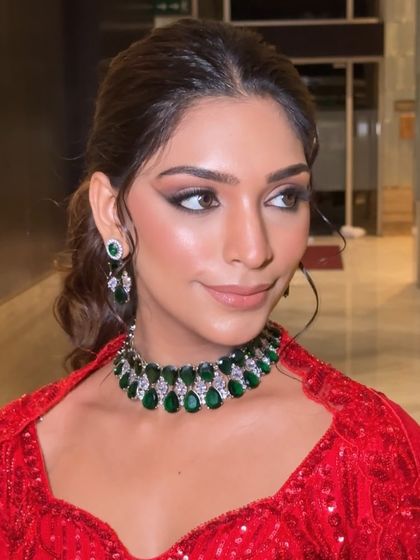 A close-up of the model's face, her smoky eye makeup perfectly complementing the deep green of the emerald choker.