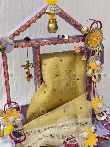 A beautiful Teej hamper featuring a traditionally decorated stand holding a 'saree'. The attention to detail makes it a truly special gift for the occasion.