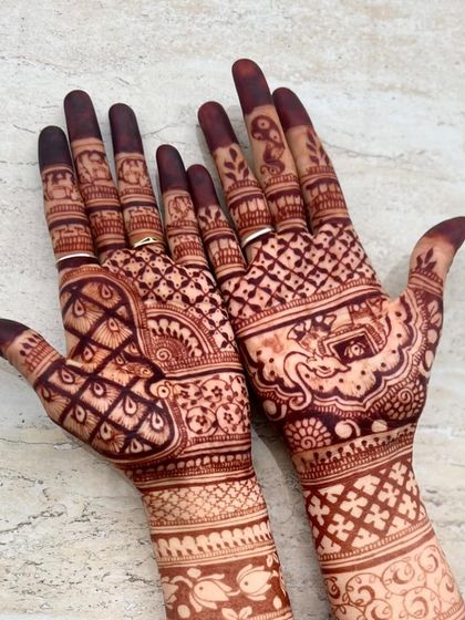 A close-up of the palms, highlighting the fish and bird motifs within the design.