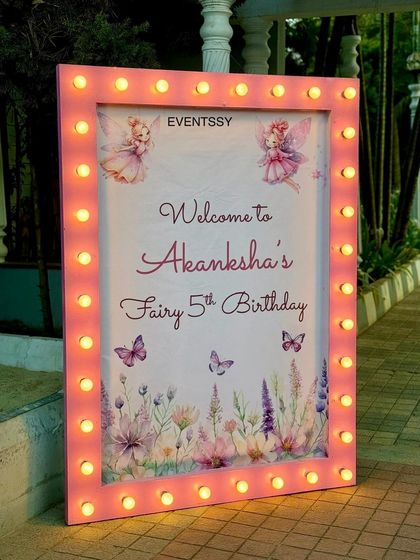 A beautiful welcome sign for the fairy-themed 5th birthday, framed with marquee lights. The sign features delicate fairy and butterfly illustrations, setting a magical tone from the entrance.