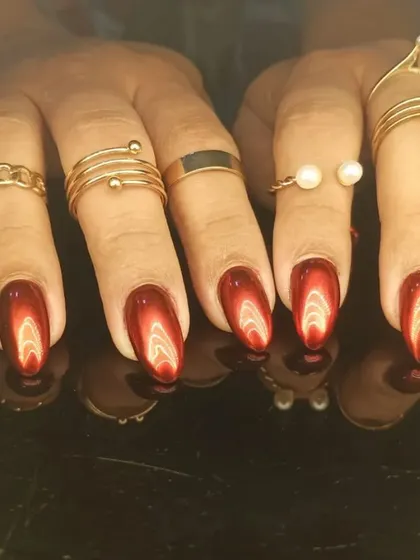 Another view of the rich, red cat-eye manicure, styled with gold rings.