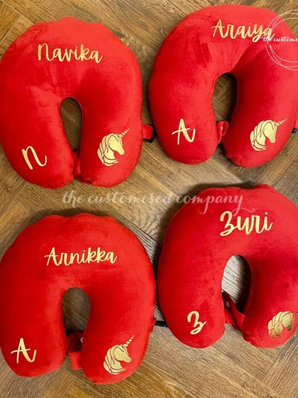 A unicorn-themed travel essential for your little one. This set of bright red personalized neck pillows is perfect for ensuring comfort on long journeys, each customized with a name and initial.
