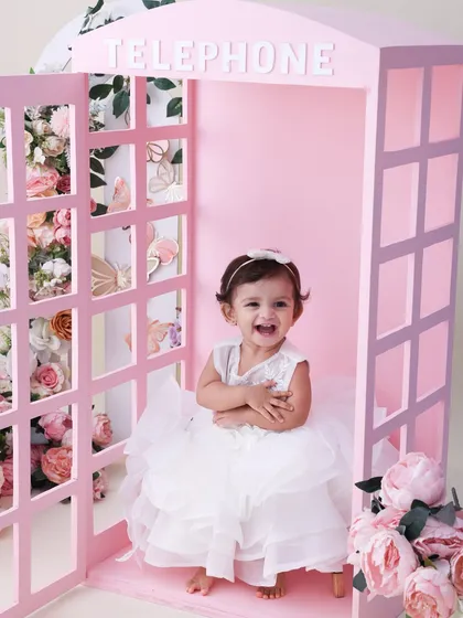 A call from a fairytale. This pink telephone booth, surrounded by beautiful blossoms, is a whimsical and charming setup for a toddler shoot. Her joyful laugh completes this magical picture.