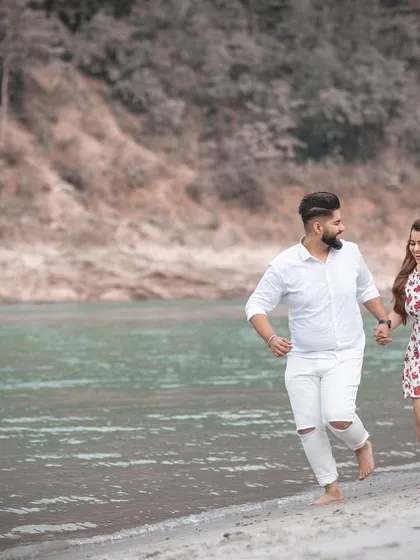 A candid action shot of the couple running along the water's edge, capturing their fun and energetic connection.
