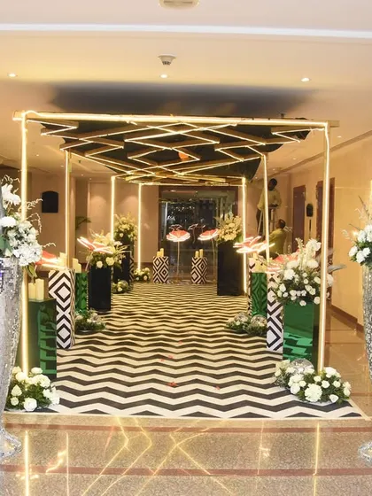 This modern and edgy entrance features a black-and-white chevron walkway, geometric structures, and tall silver vases, perfect for a contemporary cocktail party.
