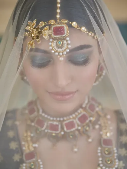 A dreamy, artistic shot of a bride through her veil. The focus is on her beautiful teal and black smokey eyes.