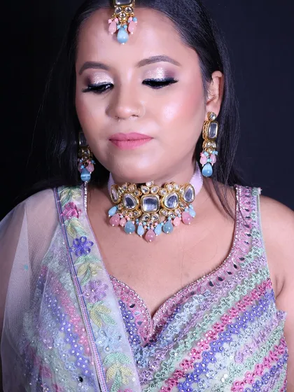 A happy client ready for her engagement in a pastel multi-color lehenga. The intricate beadwork and soft colors make it a perfect choice for a day function.