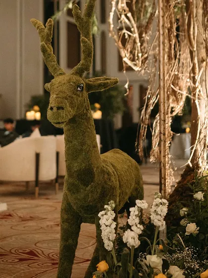 The moss deer standing amidst white flowers, creating a beautiful contrast and adding to the enchanted forest ambiance.