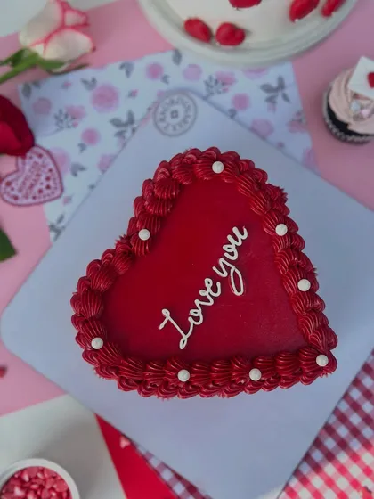 A top-down view of the red heart-shaped "Love you" cake, showcasing its rich color and delicate piping.