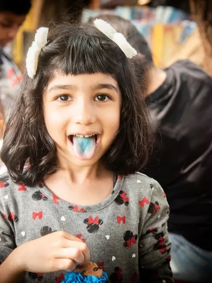 Birthday party fun. This candid shot captures a girl's playful side, sticking out her blue tongue for the camera.