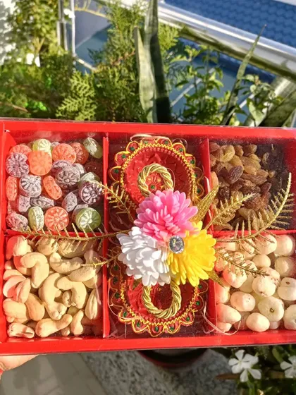 An affordable Diwali gifting box with five compartments, filled with cashews, raisins, candies, and decorative diyas.