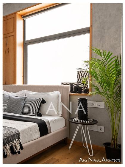 A detail shot of the bedside in a guest room of Apartment 7 cemento-textured walls and a large window with a wooden frame create a bright and modern feel.