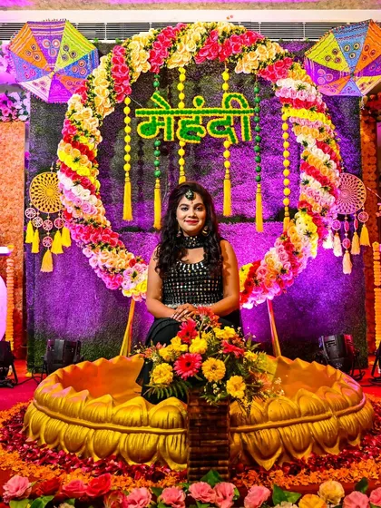 A full view of the bride seated against a stunning and colorful Mehndi decor setup. We make sure to capture the scale and beauty of your event's design.