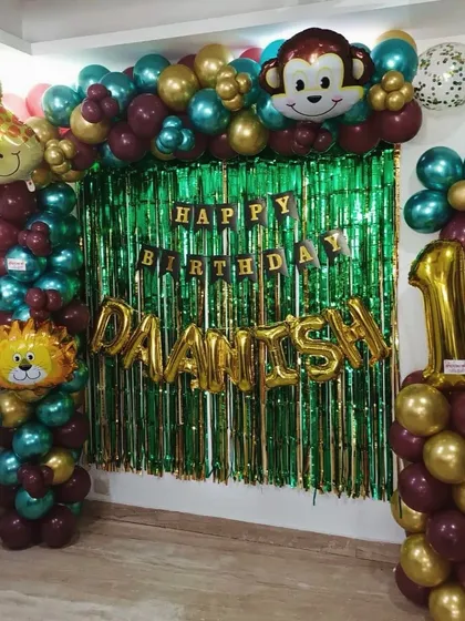 A compact jungle theme setup perfect for home celebrations. It includes a green foil curtain backdrop, a 'Happy Birthday' banner, and balloon pillars with cute lion and monkey foil balloons.