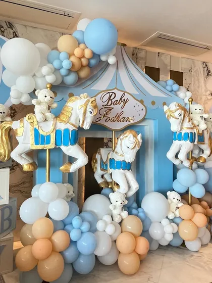 To welcome a baby boy, we designed a beautiful carousel-themed setup with pastel blue and peach balloons, classic carousel horses, and adorable teddy bears.